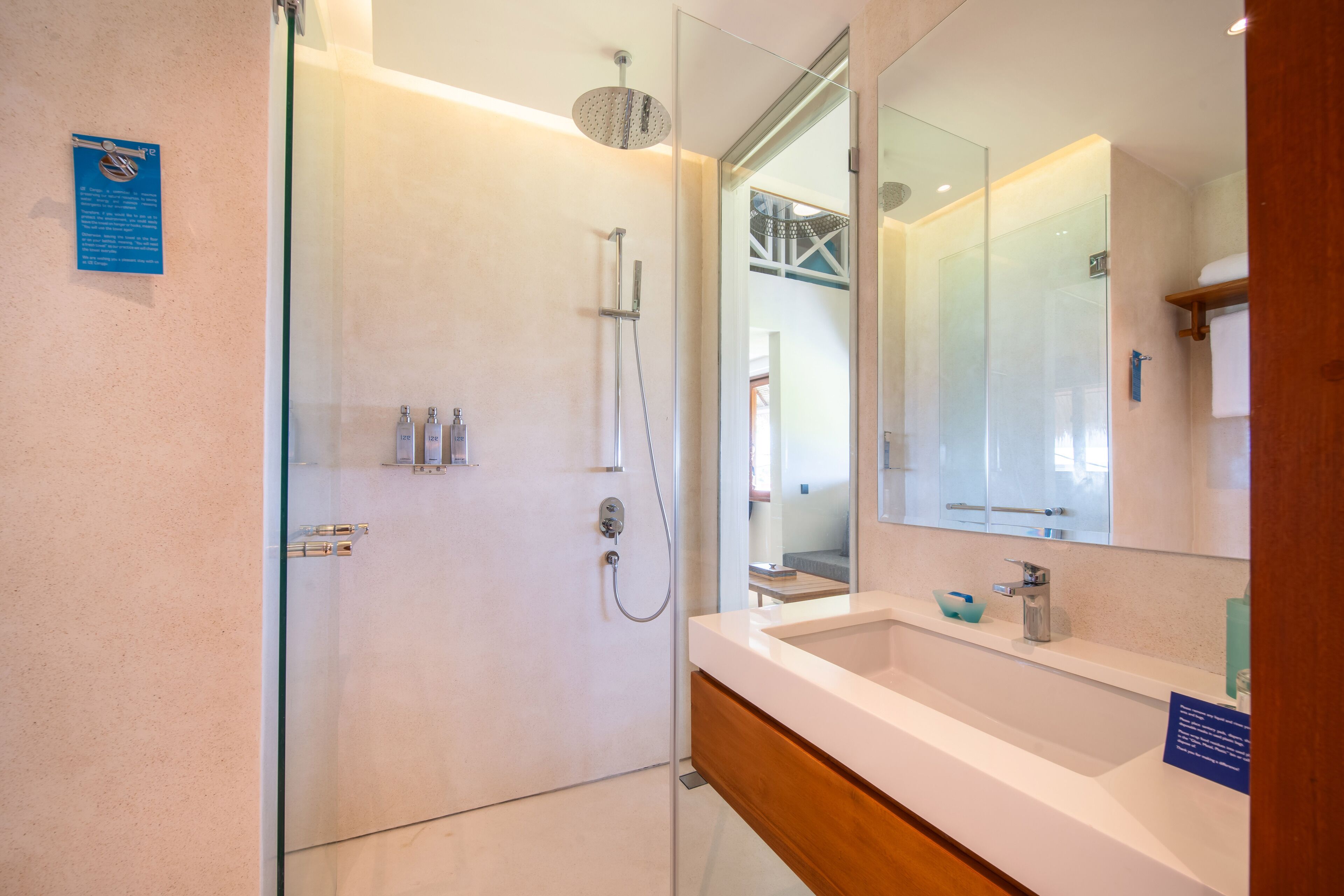 A modern bathroom with a glass shower enclosure, a white sink, and a large mirror.
