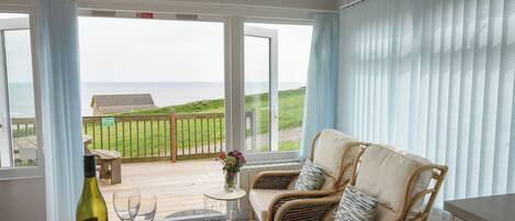 A balcony with wicker furniture, a bottle of wine, and two glasses.