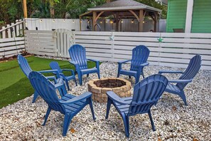 A circular seating arrangement around a fire pit with chairs and a stone fire pit. - Magnolia Cove - Fire Pit, Hot Tub, Downtown (St. Augustine)