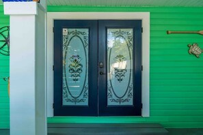 A double door with intricate designs, a green exterior wall, and a small decorative item above the door.