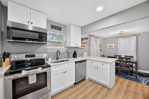 A modern kitchen with white cabinetry, a built-in microwave, and a dishwasher.