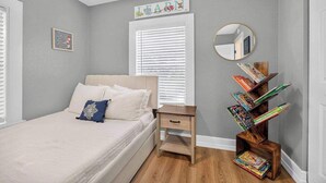Quarto com cama, mesa de cabeceira e uma estante de madeira.