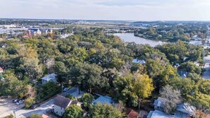 An aerial view of a residential area with houses, a river, and a bridge in the background.