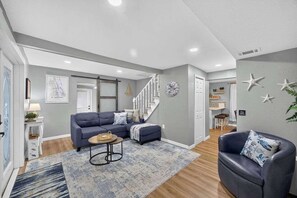 A modern living room with a sectional sofa, a coffee table, and a staircase leading to another level.