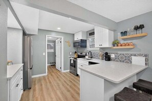 A modern kitchen with white cabinetry, a central island, and a backsplash with a floral pattern.