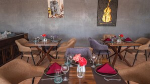 Un interior de restaurante con mesas y sillas de madera, y obras de arte en las paredes.