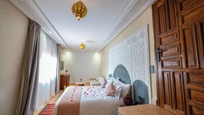 Una habitación de hotel con una cama, un armario de madera, un zócalo decorativo y una araña.