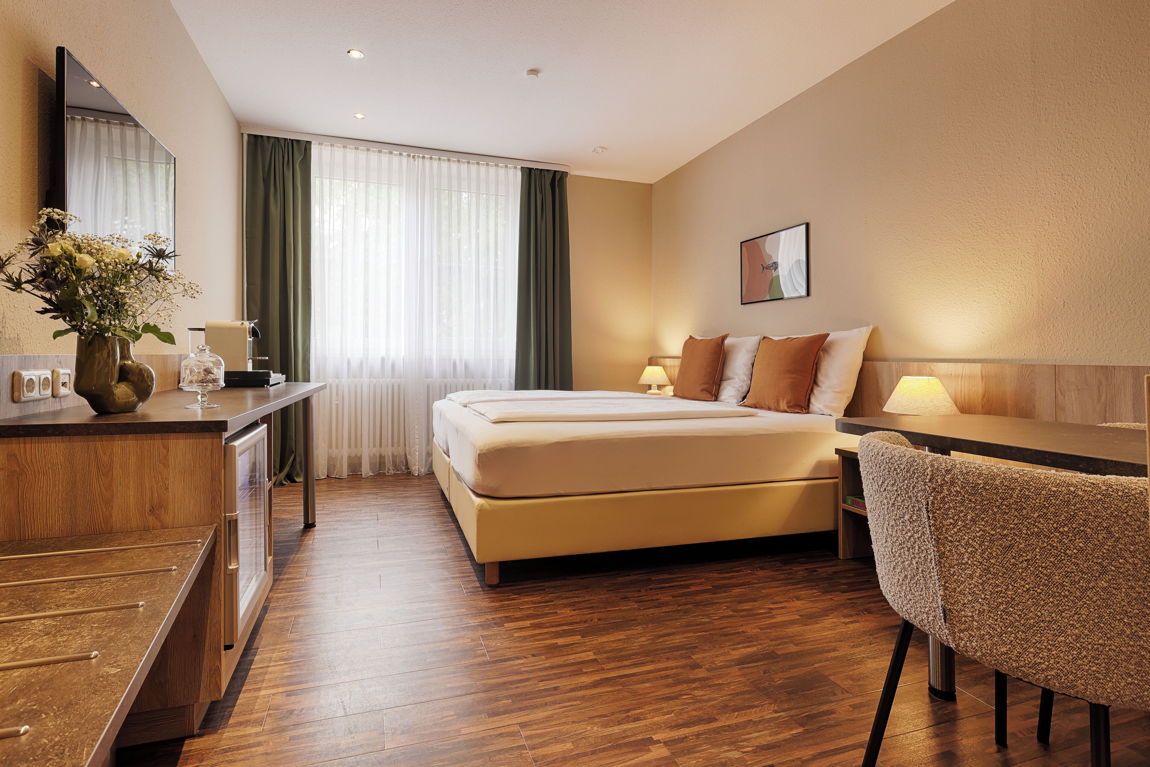 Ein Hotelzimmer mit Bett, Nachttischen, Schreibtisch und Stuhl.