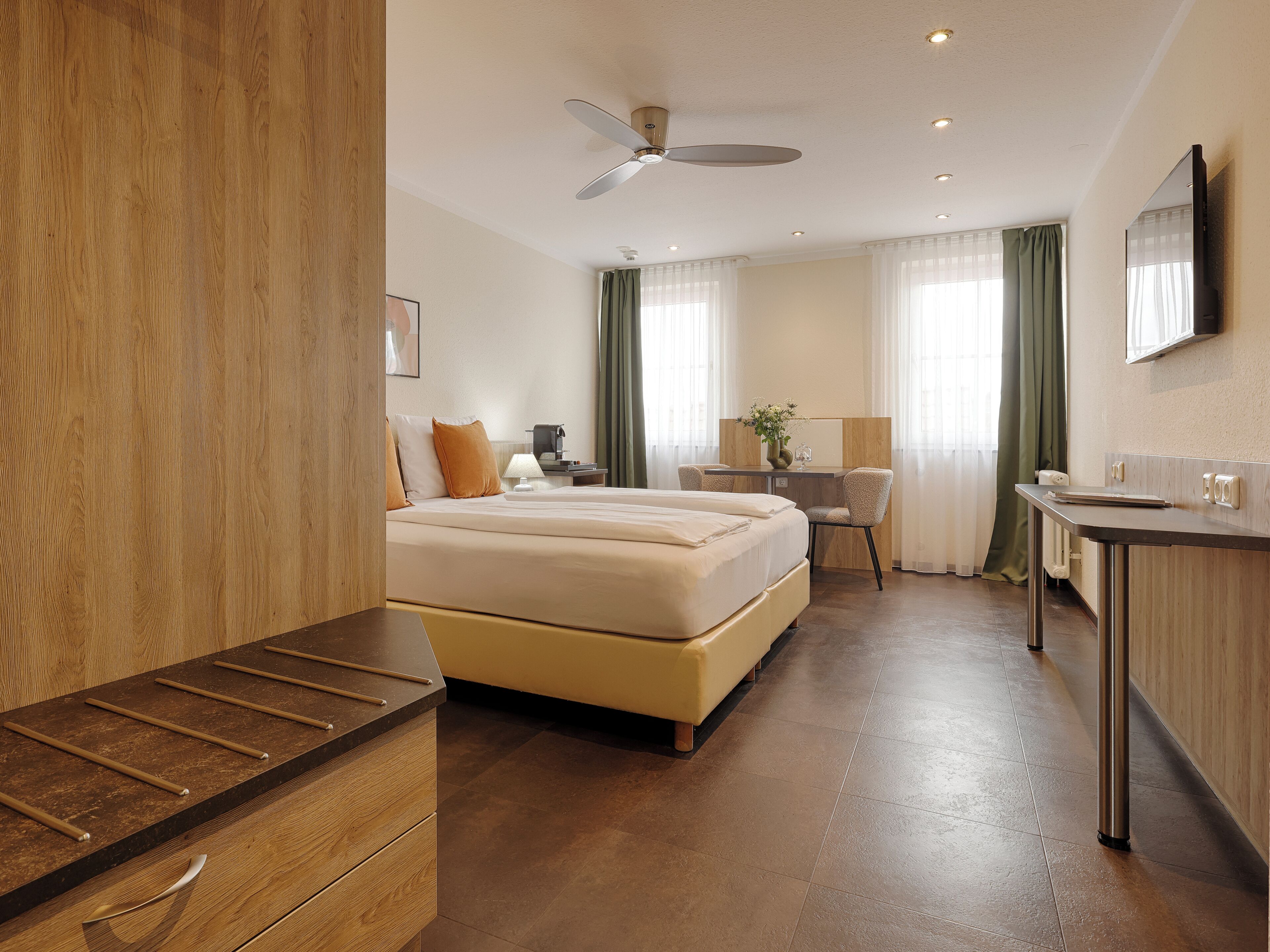 Habitación de hotel con cama, escritorio, silla y una pequeña cocina.