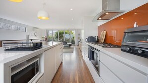 A modern kitchen with a central island, a built-in oven, and a stove. - Silver Ball Retreat (Warrnambool)