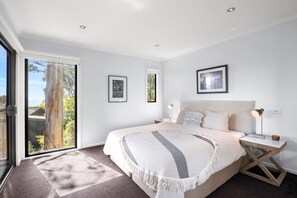 A bedroom with a large bed, a nightstand, a lamp, and a picture on the wall. - The Eyrie (Lorne)