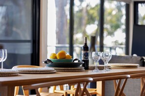 A dining table with a bottle of wine, glasses, and a bowl of lemons. - The Eyrie (Lorne)