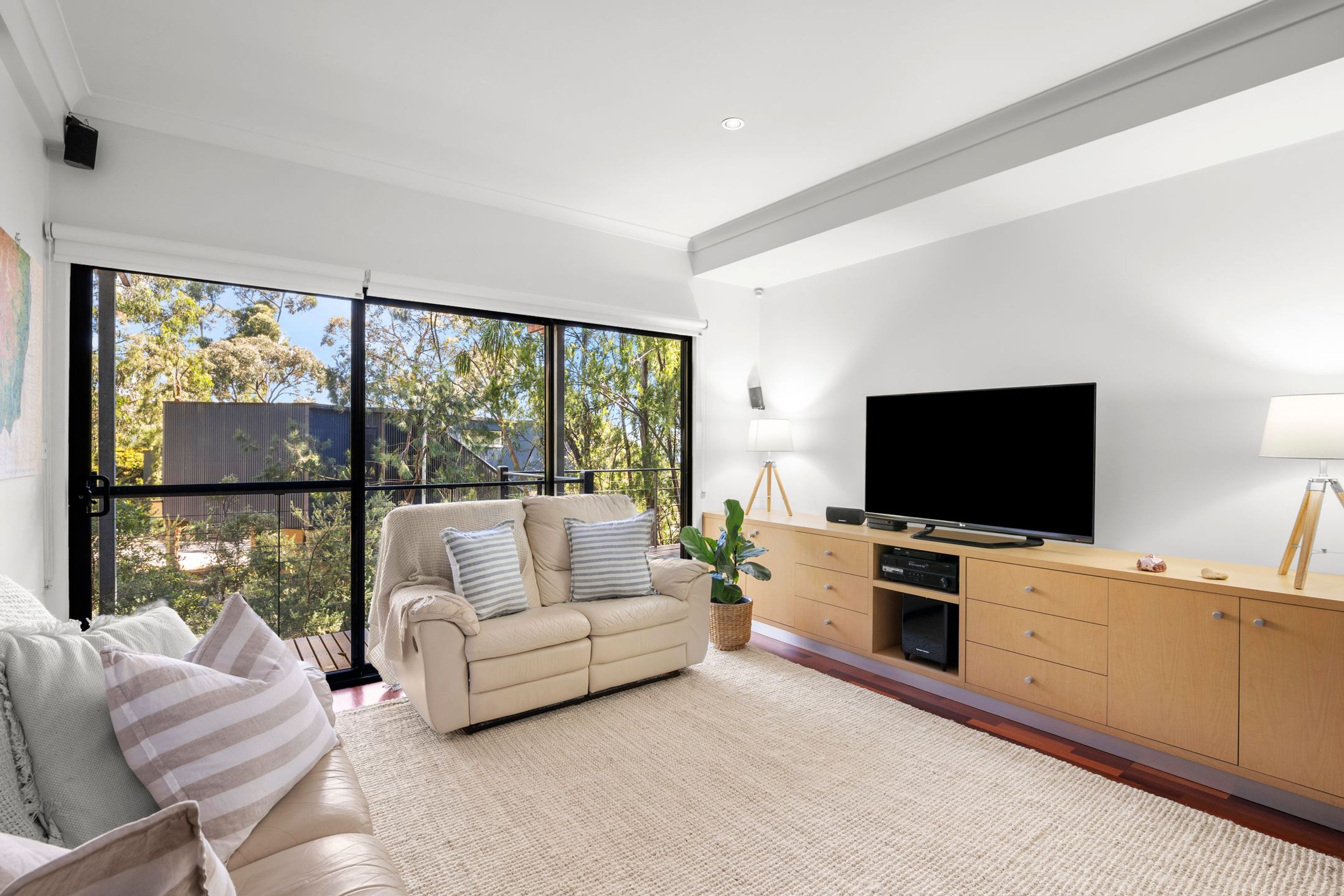 A modern living room with a sofa, TV, and wooden cabinet.