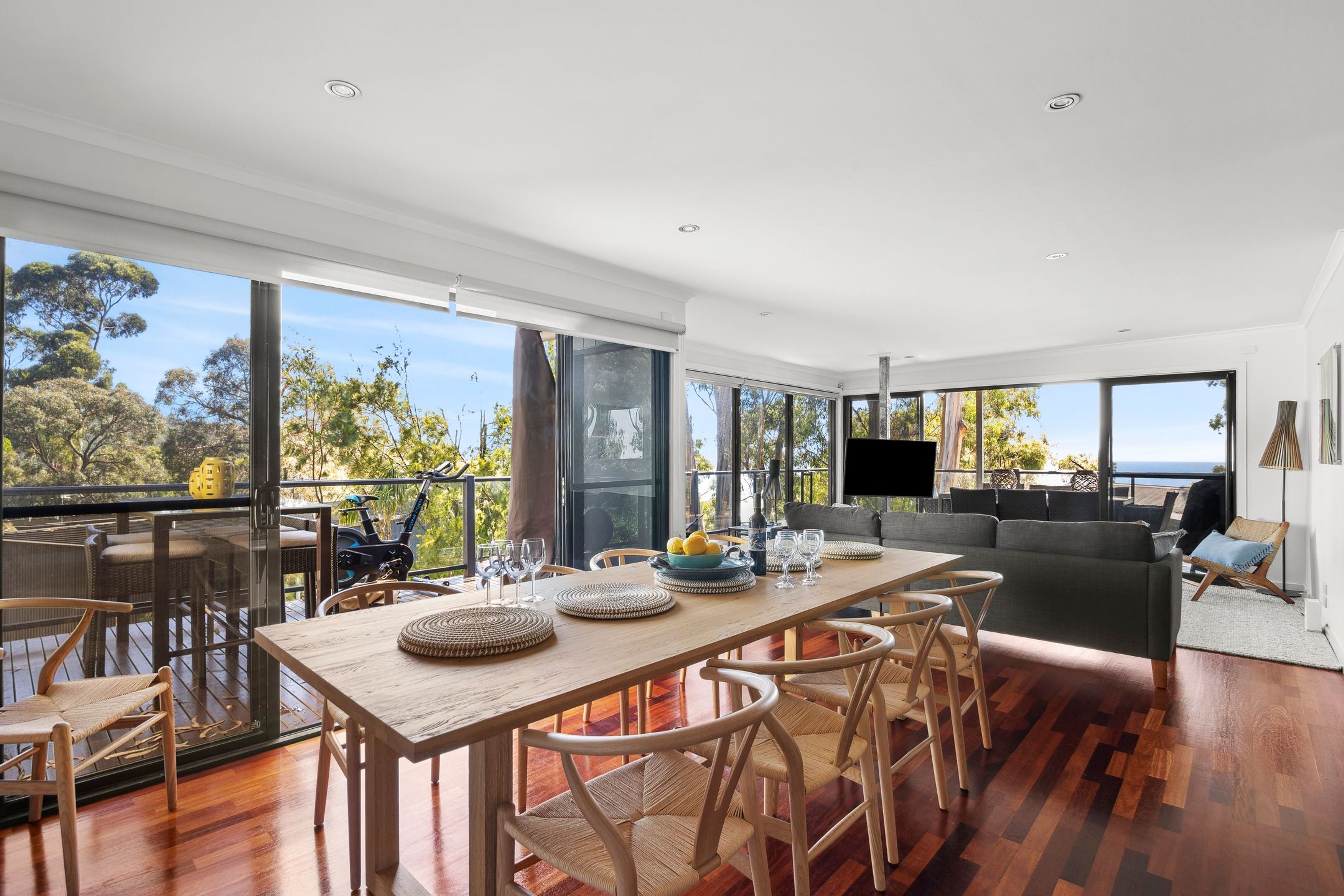A spacious living area with a large wooden dining table, multiple chairs, a sofa, and a television.