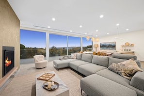 A modern living room with a fireplace, a large sectional sofa, and a dining area with a view. - Casa Lux Aireys Inlet Retreat with Heated Pool Spa (Aireys Inlet)