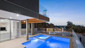 Un espace piscine extérieur moderne, doté de rampes en verre et offrant une vue dégagée sur le ciel.