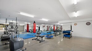 Une salle de sport équipée de divers appareils d’exercice, notamment des tapis de course, des appareils de musculation et une table de baby-foot.