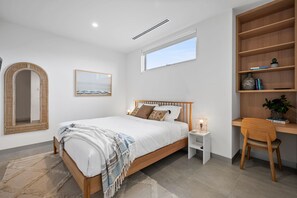 Une chambre à coucher moderne avec un lit en bois, une table de chevet avec une lampe, une bibliothèque et un grand miroir.