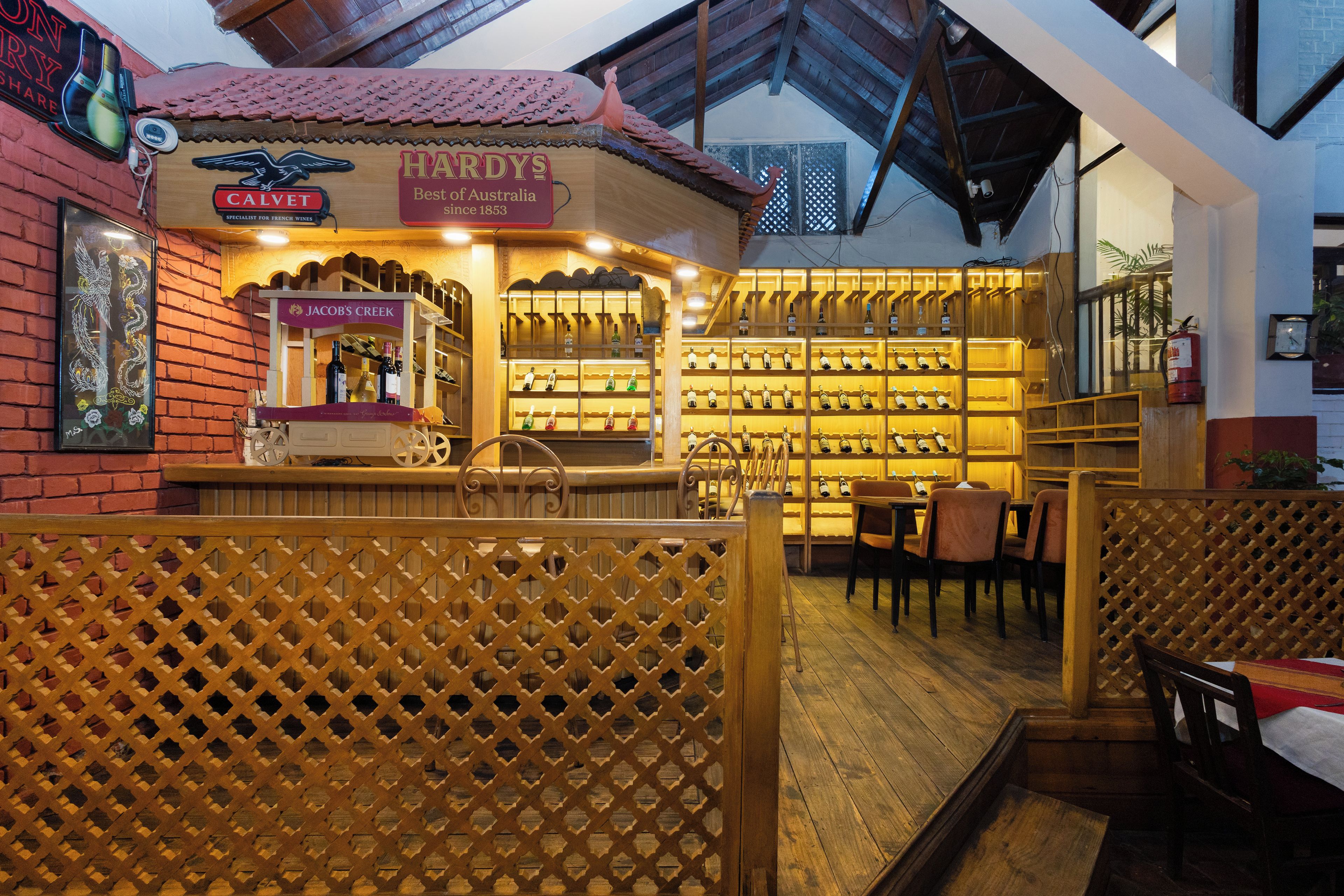 Zona de bar interior con muebles de madera y una vitrina de vinos.