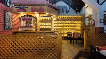 Zona de bar interior con muebles de madera y una vitrina de vinos.