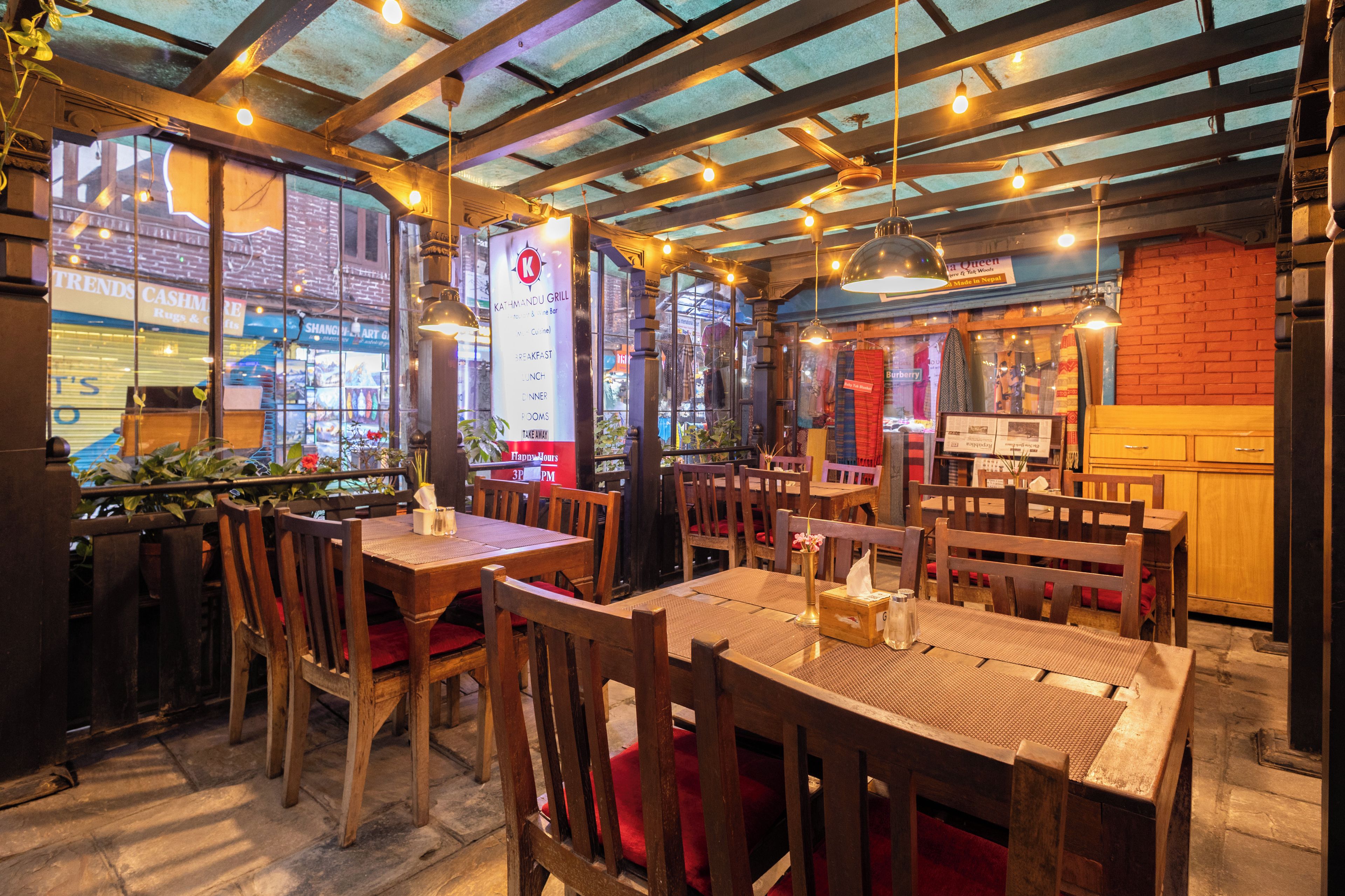 A restaurant interior with wooden tables and chairs, a bar area, and a view of the street outside.