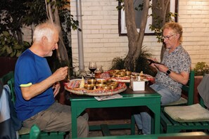 Two individuals seated at a table with a variety of dishes and a glass of red wine.