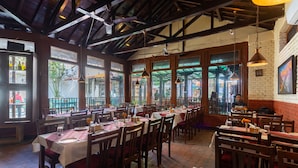 A restaurant with wooden tables and chairs, large windows, and hanging pendant lights. - Aawas Boutique Hotel (Kathmandu)
