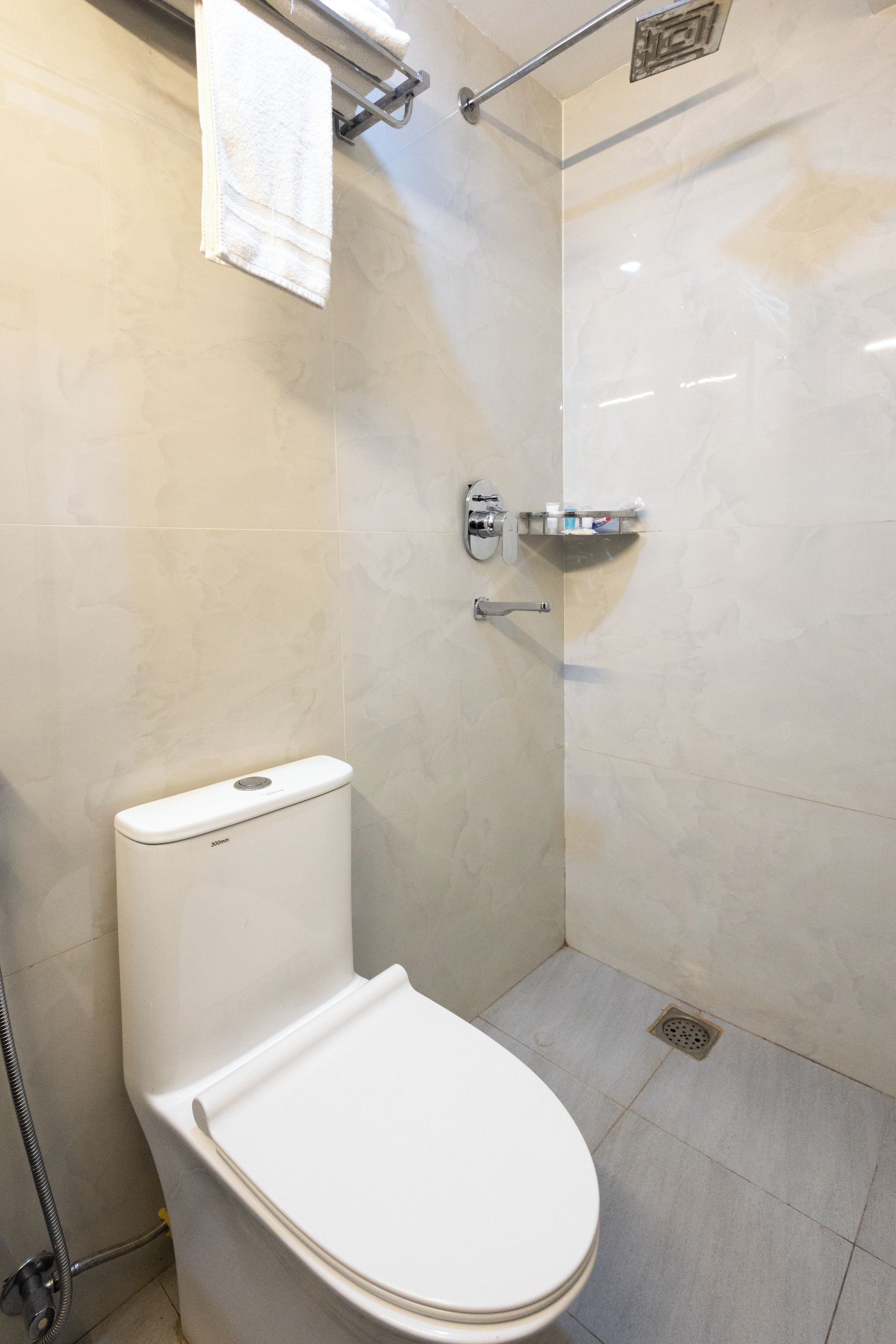 A modern bathroom with a toilet, a shower, and a towel rack.