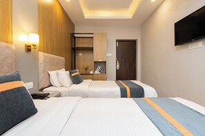 A hotel room with two beds, a flat-screen TV mounted on the wall, and a wooden cabinet.