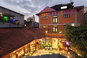 A courtyard with outdoor seating, a brick building, and string lights. - Aawas Boutique Hotel - Central Thamel (Kathmandu)