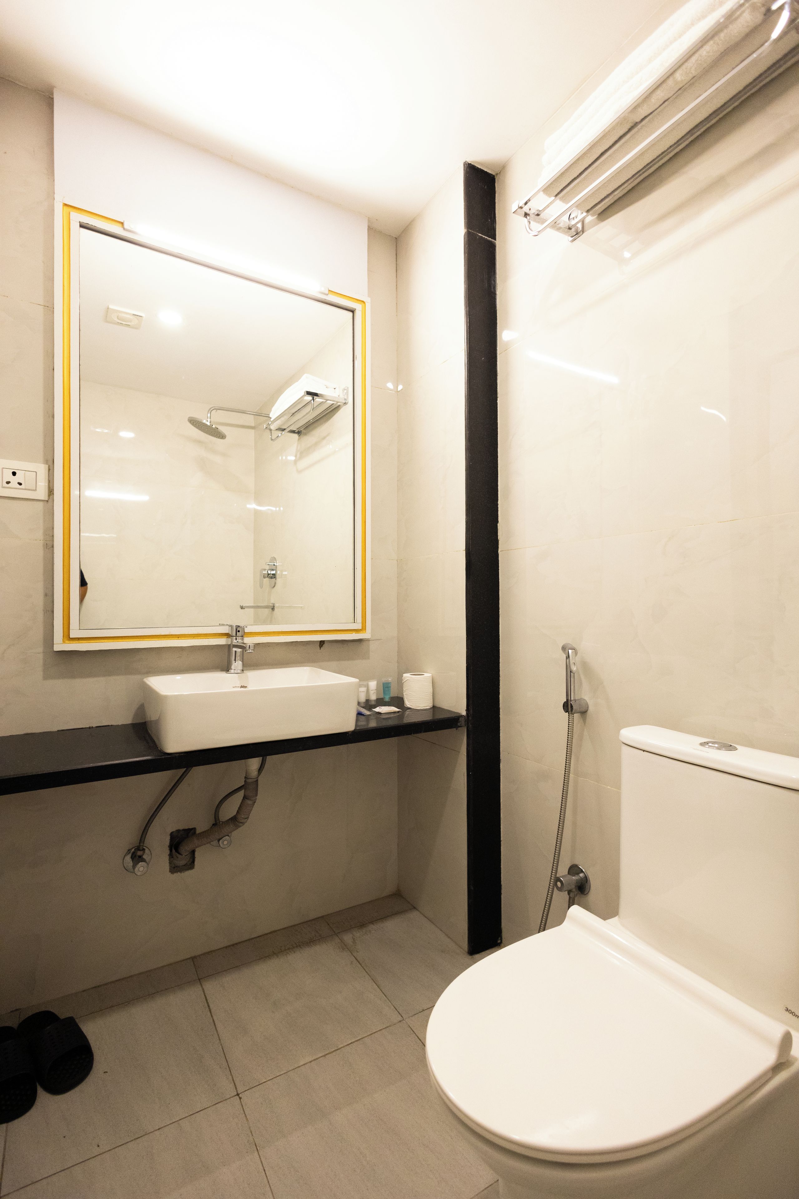Un baño moderno con un lavabo blanco, un espejo con marco dorado, ducha e inodoro.