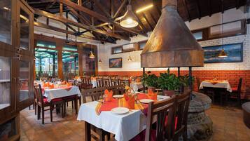 Un restaurante con paredes de ladrillo, vigas de madera y mesas dispuestas para comer.