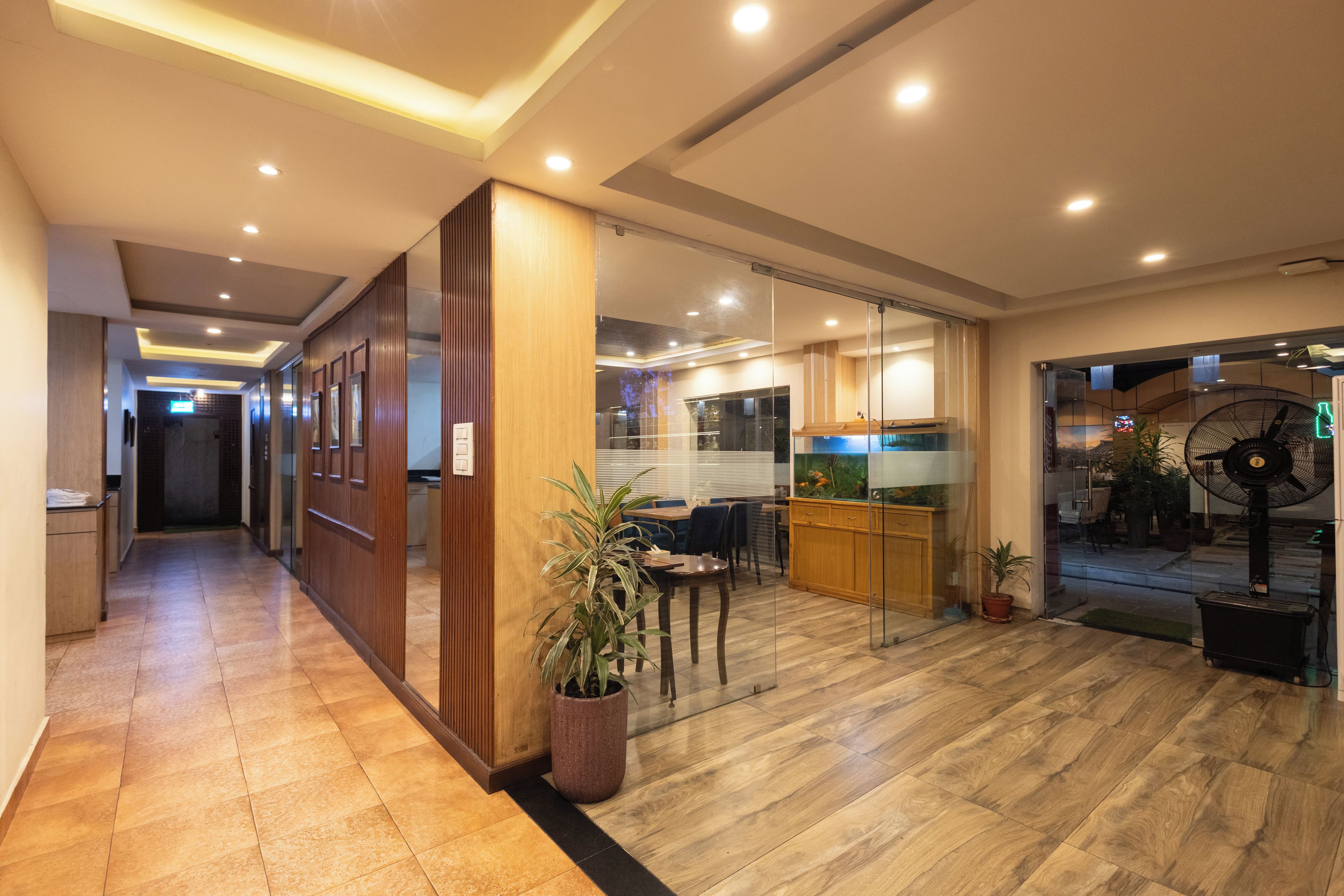 A hotel lobby with a reception desk, a seating area with a plant, and a large aquarium.