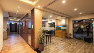 A hotel lobby with a reception desk, a seating area with a plant, and a large aquarium.