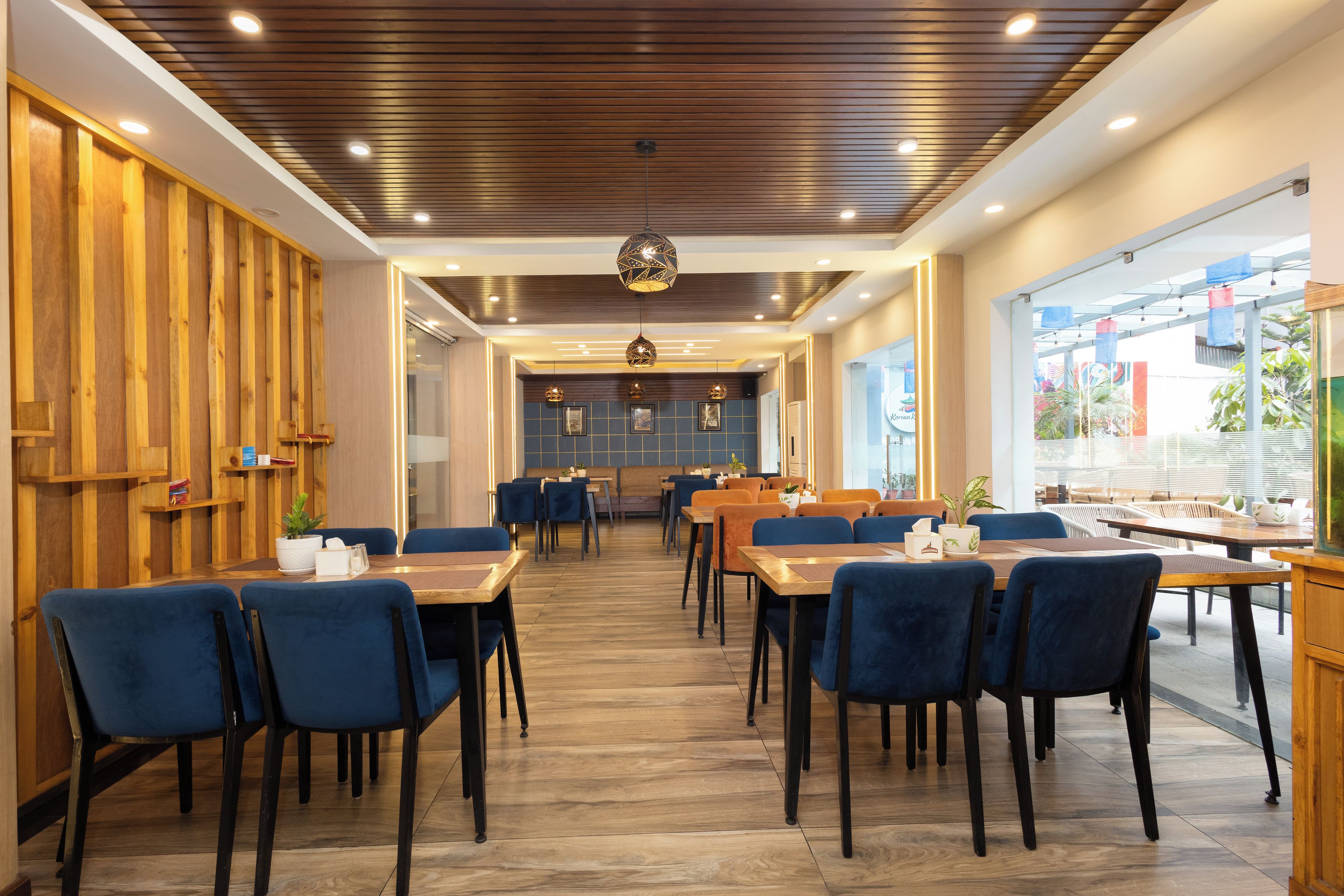 Un restaurante moderno con paneles de madera, sillas azules y una zona de comedor central.
