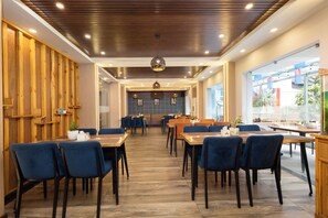 A modern restaurant with wooden paneling, blue chairs, and a central dining area. - Aawas Boutique Hotel - Central Thamel (Kathmandu)