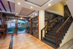 A hotel lobby with a staircase, seating area, and a view of the street. - Aawas Boutique Hotel - Central Thamel (Kathmandu)