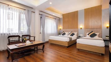 Habitación de hotel con dos camas, una mesa de madera, sillas y un escritorio con una computadora.