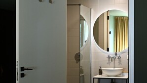 A modern bathroom with a glass shower enclosure, a round mirror, and a white sink. - Wapen van Hengelo Residence Suites - LOGIES ONLY - digital key by APP and email (Hengelo)