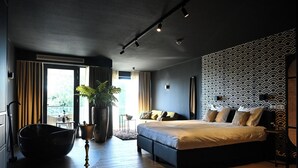 A modern bedroom with a large bed, a potted plant, and a view of the outdoors. - Wapen van Hengelo Residence Suites - LOGIES ONLY - digital key by APP and email (Hengelo)