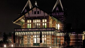 A large, illuminated building with a prominent central tower and a balcony. - Wapen van Hengelo Residence Suites - LOGIES ONLY - digital key by APP and email (Hengelo)