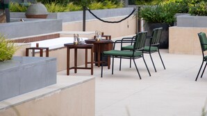 An outdoor seating area with a modern building in the background. - Artyzen NEW BUND 31 Shanghai (Shanghai)