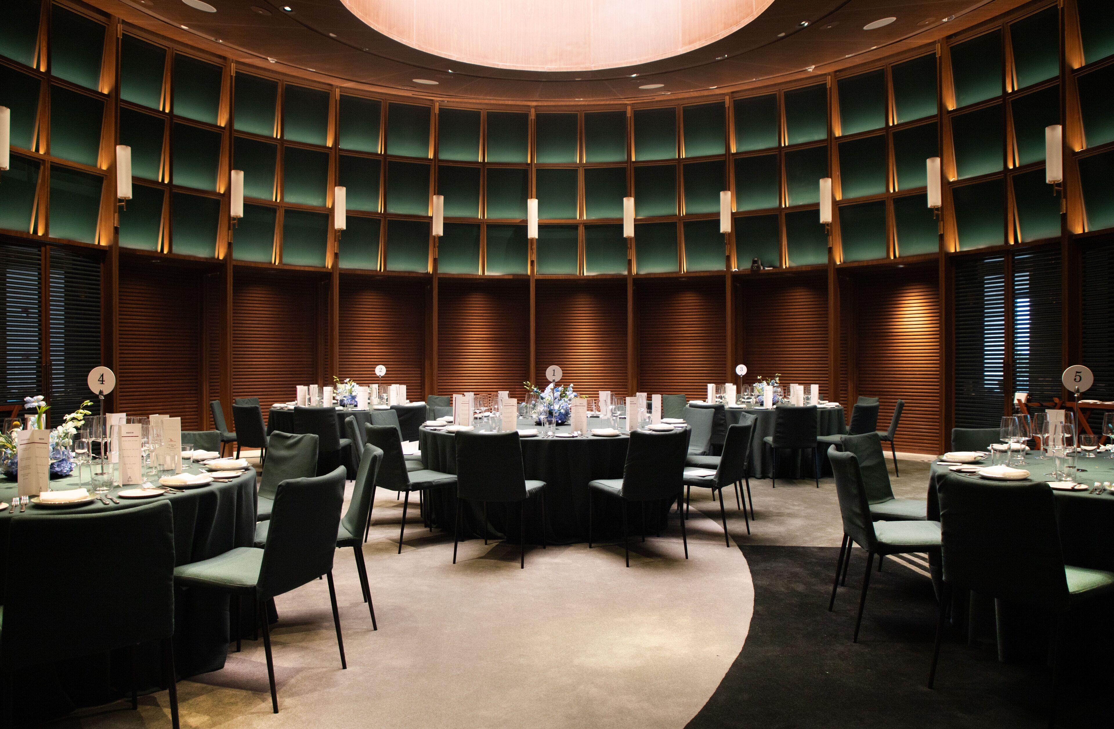 Een congreszaal met meerdere ronde tafels, elk voorzien van stoelen, glazen en decoratieve middelpunt.