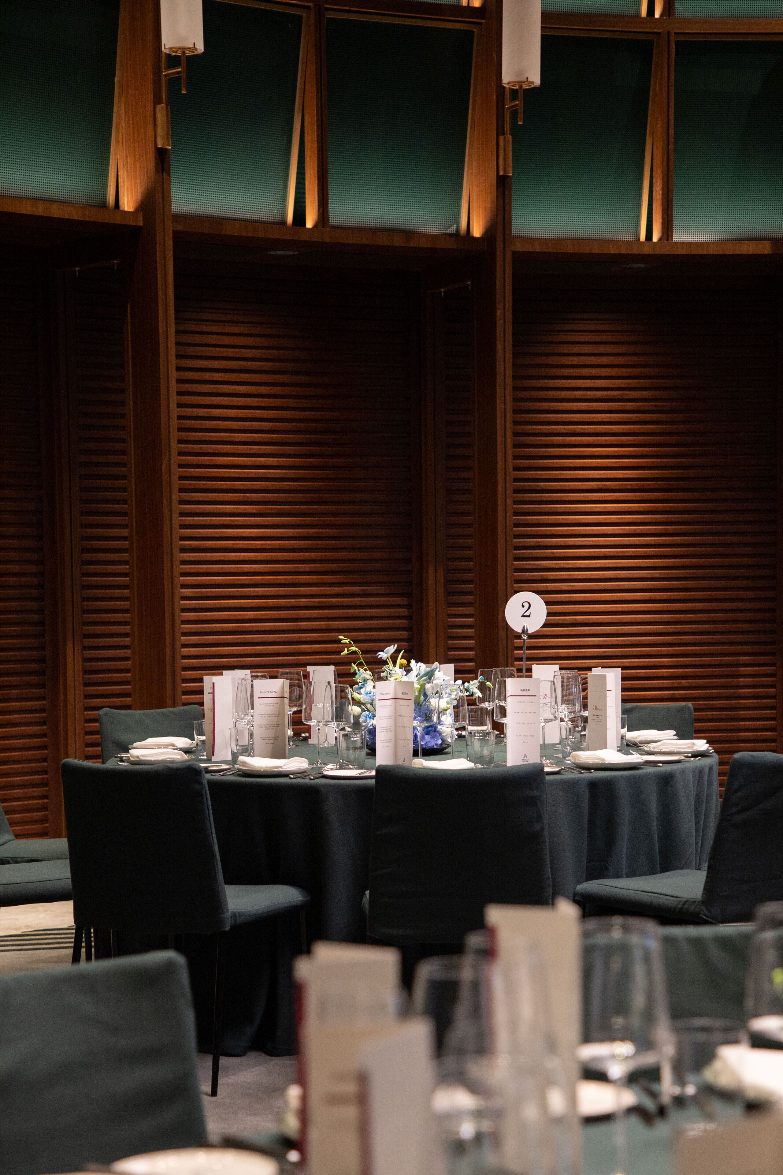 Un salón de conferencias con una mesa dispuesta para una reunión, número 2, frente a un panel de madera.