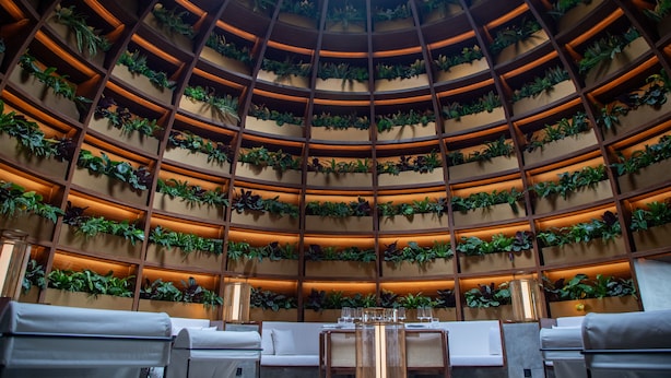 A circular interior with tiered shelving filled with plants, seating areas, and tables. - Artyzen NEW BUND 31 Shanghai (Shanghai)