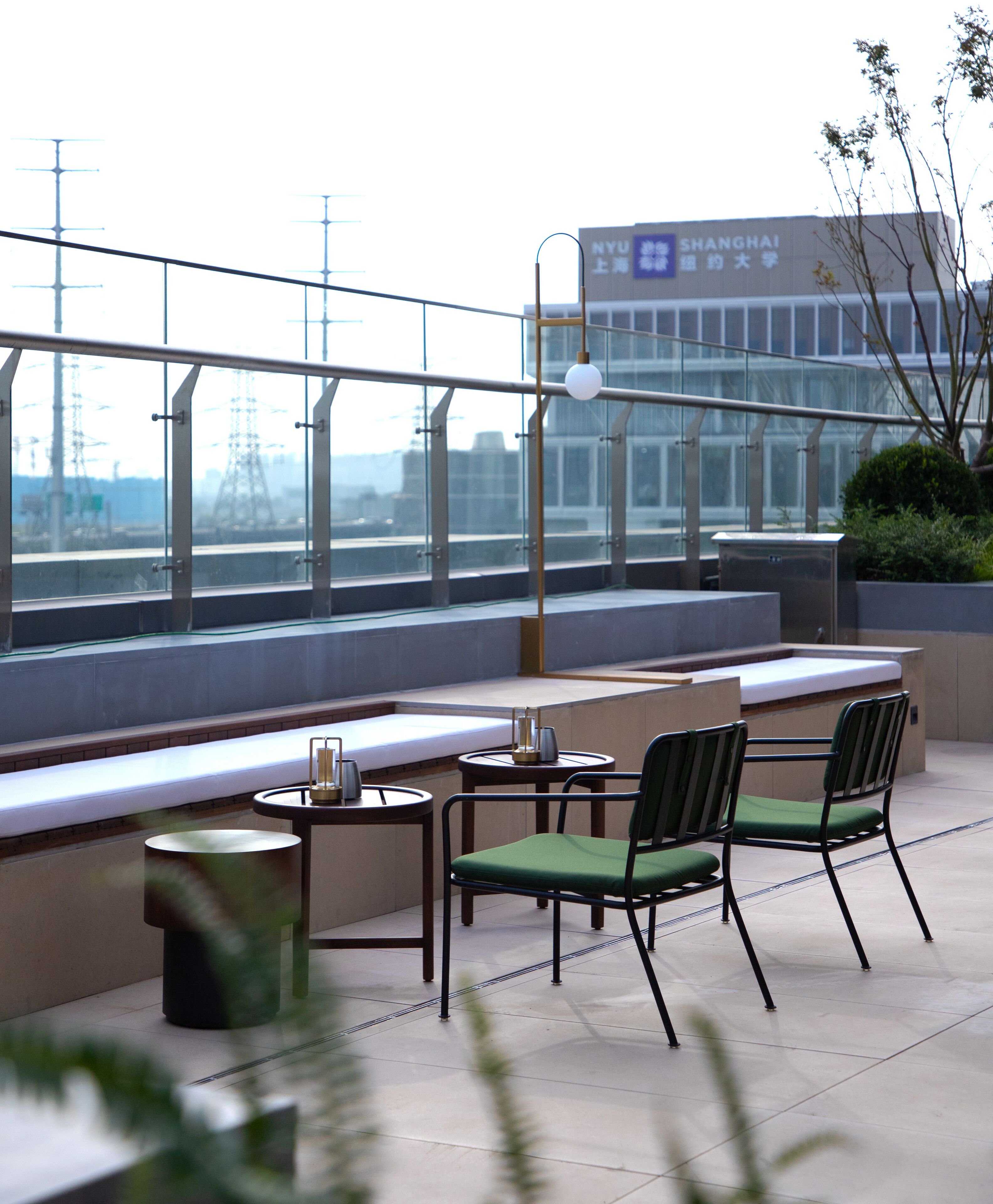 A rooftop terrace with a table and chairs, a lamp, and a view of a building with signage.