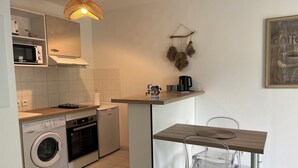 Une cuisine compacte équipée d’un lave-linge, d’un four, d’un four à micro-ondes et d’un luminaire suspendu.