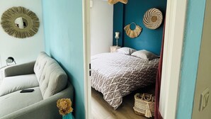 Une chambre moderne comprenant un lit, un canapé, un miroir et des éléments décoratifs muraux.