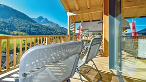 A wooden deck with a view of mountains, a barbecue grill, and outdoor seating.