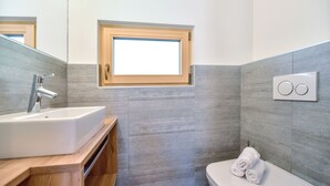 A modern bathroom with a sink, toilet, and a small window.